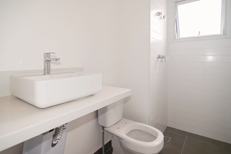 Banheiro com bancada, cuba, bacia e piso de porcelanato
