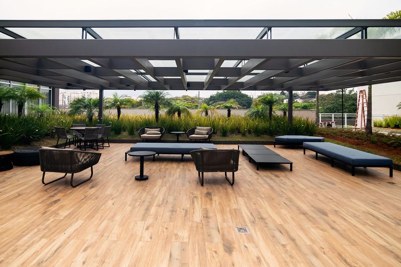 Lounge externo com pergolado, deck de madeira e poltronas
